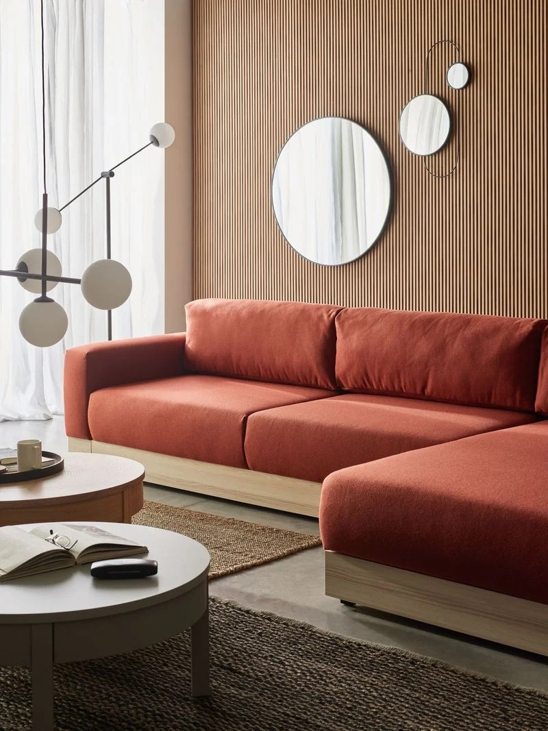 Przytulny salon z ceglastą sofą, lamelową ścianą i designerskimi lustrami.